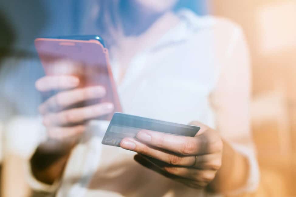 Shopping online with smartphone and credit card on hand.