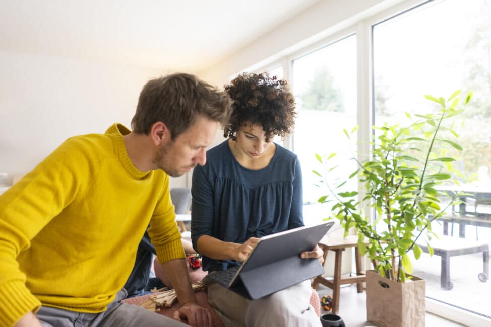 Couple sitting in living room, using digital tablet