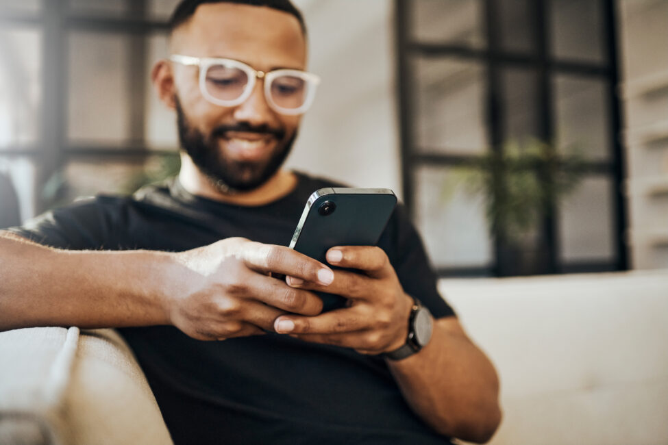 A man on the couch looking at his phone in a relaxed manner.